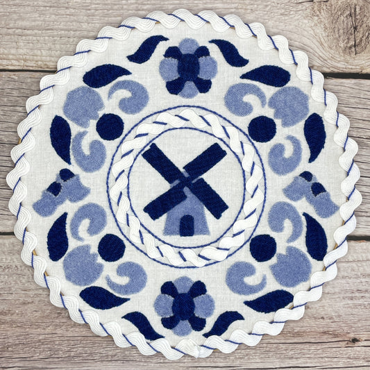 Dutch Porcelain Wool Applique Pattern. Blue wool in two shades cut into traditional Dutch shapes such as windmill, tulips, and shoes. Pattern is placed in a hoop to mimic delft pottery.